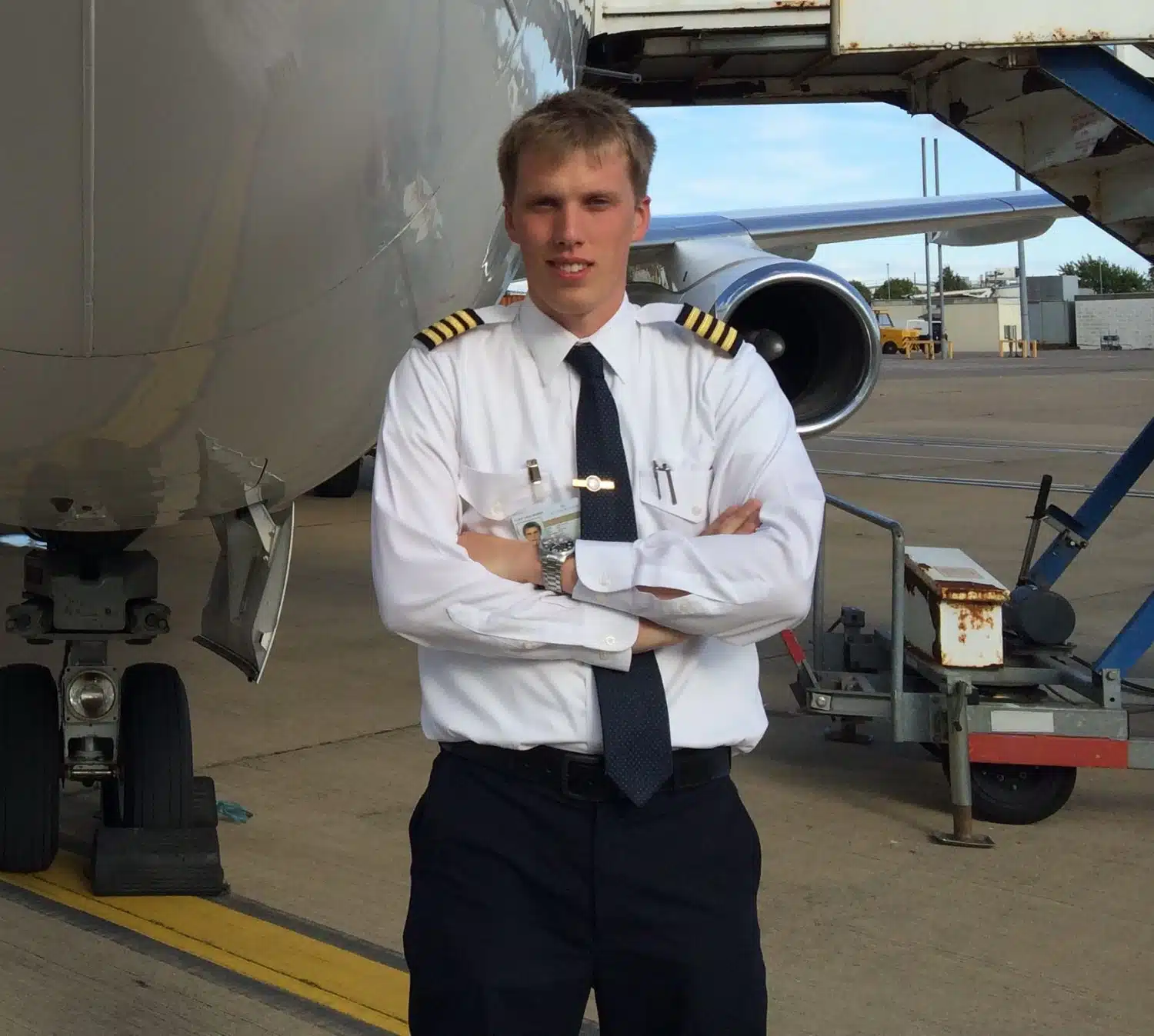 Pilot in uniform standing in front of an airplane. About.